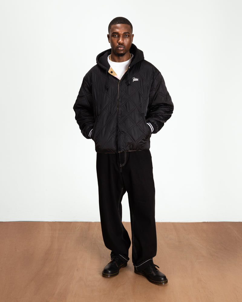 full body model shot of the black side of the reversible woodland camo bomber jacket. styled with black jeans and boots